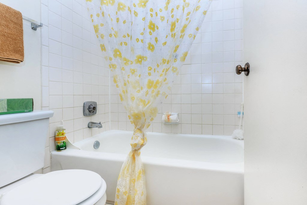 A white bathtub with a yellow shower curtain.