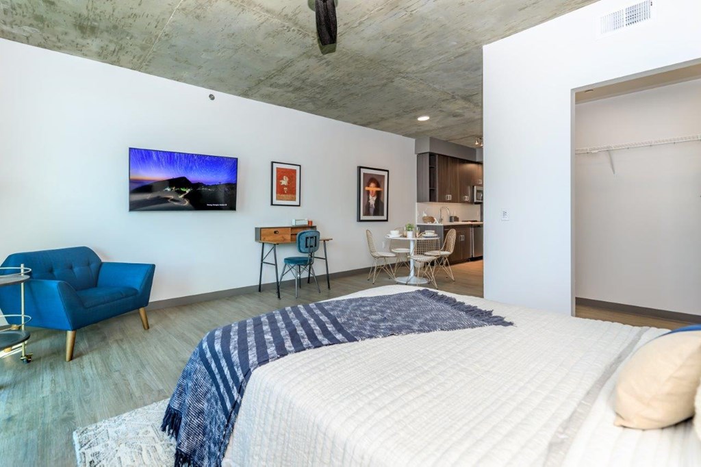 A bedroom with a bed, a chair, and a television on the wall.