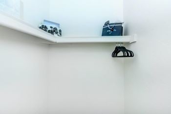 A white shelf with a black hanger on it.