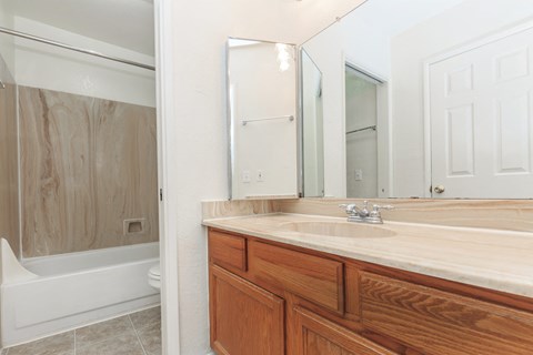 A bathroom with a wooden vanity and a white bathtub.