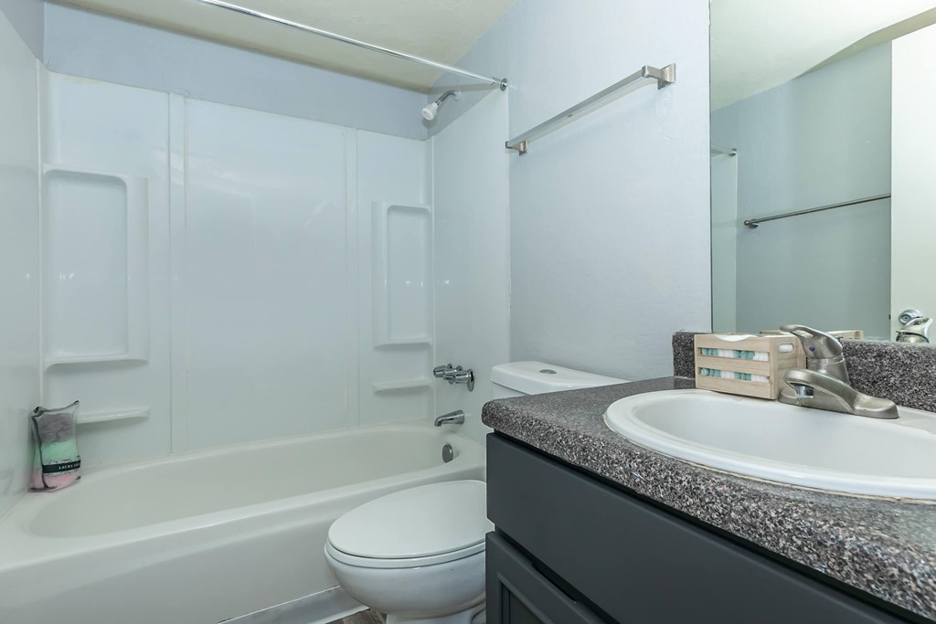A white toilet sits next to a bathtub in a bathroom.