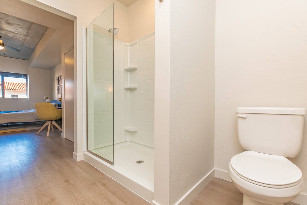 A white toilet sits in a bathroom next to a walk-in shower. at The Benedictine, Arizona, 85716