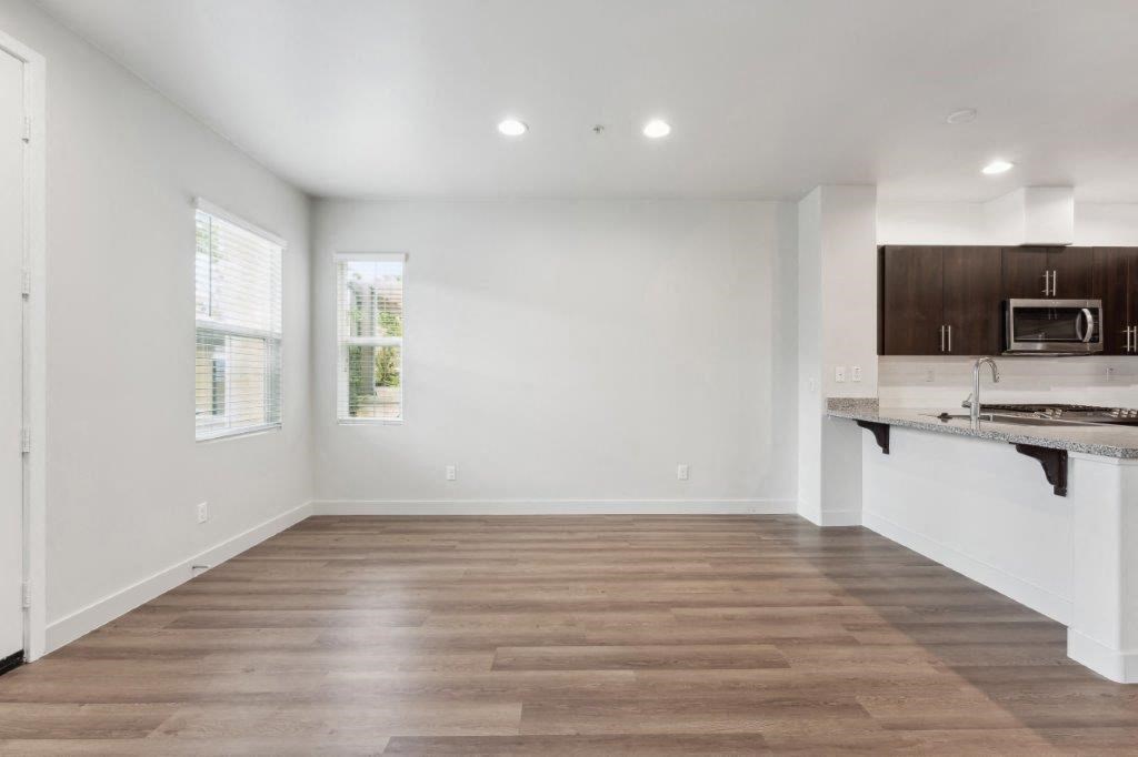 an empty living room with a kitchen with a sink and a microwave