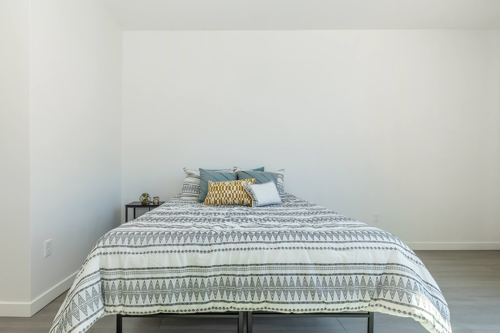 A room with a white door, a window with blinds, and a wooden floor.