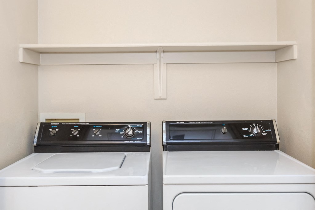 Two white washing machines in a laundry room.