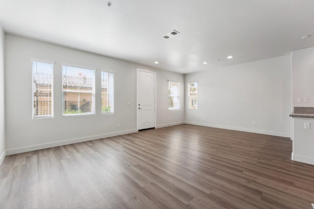 an empty living room with wood floors and white walls