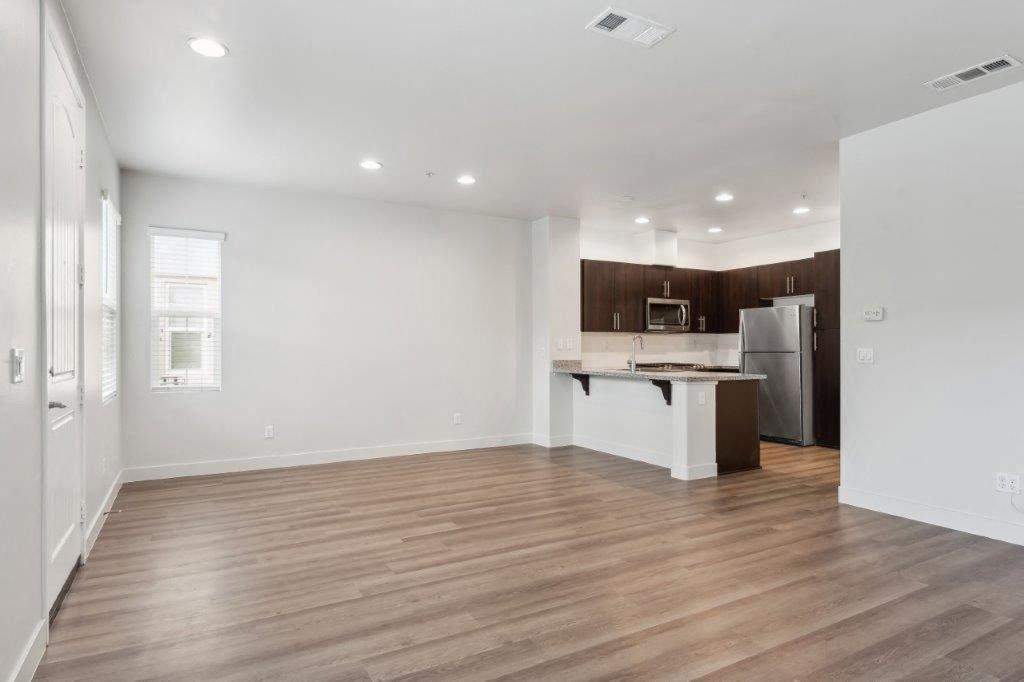 an empty living room and kitchen with a refrigerator and