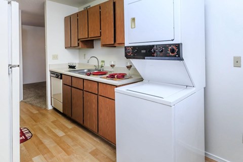 A small kitchen with a white dishwasher and wooden cabinets.
