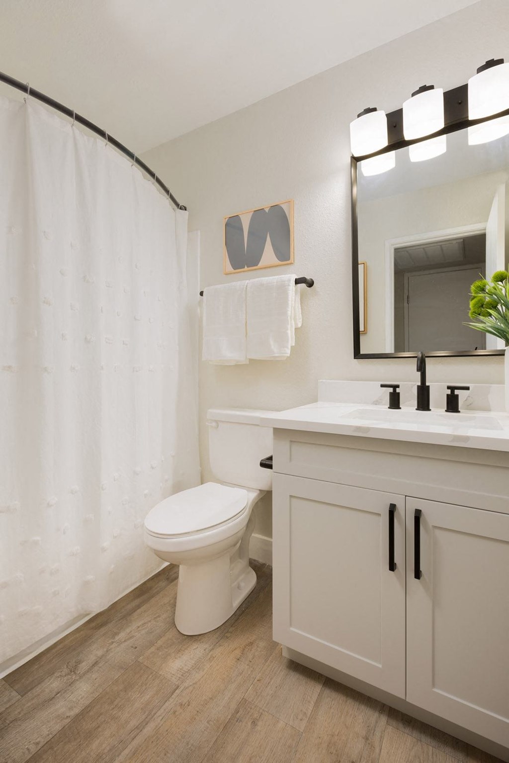 a bathroom with a white shower curtain and a white toilet next to a white sink with a