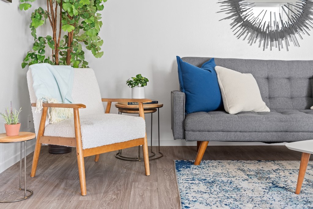 A living room with a grey couch, a wooden chair, and a small table.