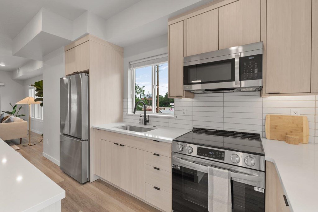 A modern kitchen with a stainless steel refrigerator, microwave, and oven.