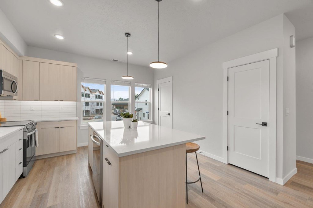 A modern kitchen with wooden floors and white walls.