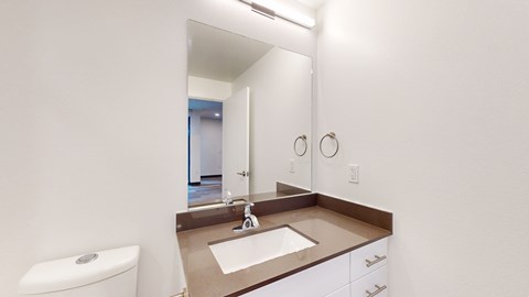 A bathroom with a sink, toilet, and mirror.
