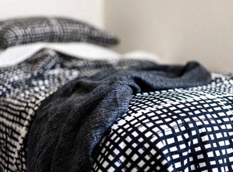 a bed with a checkered comforter and a black and white blanket
