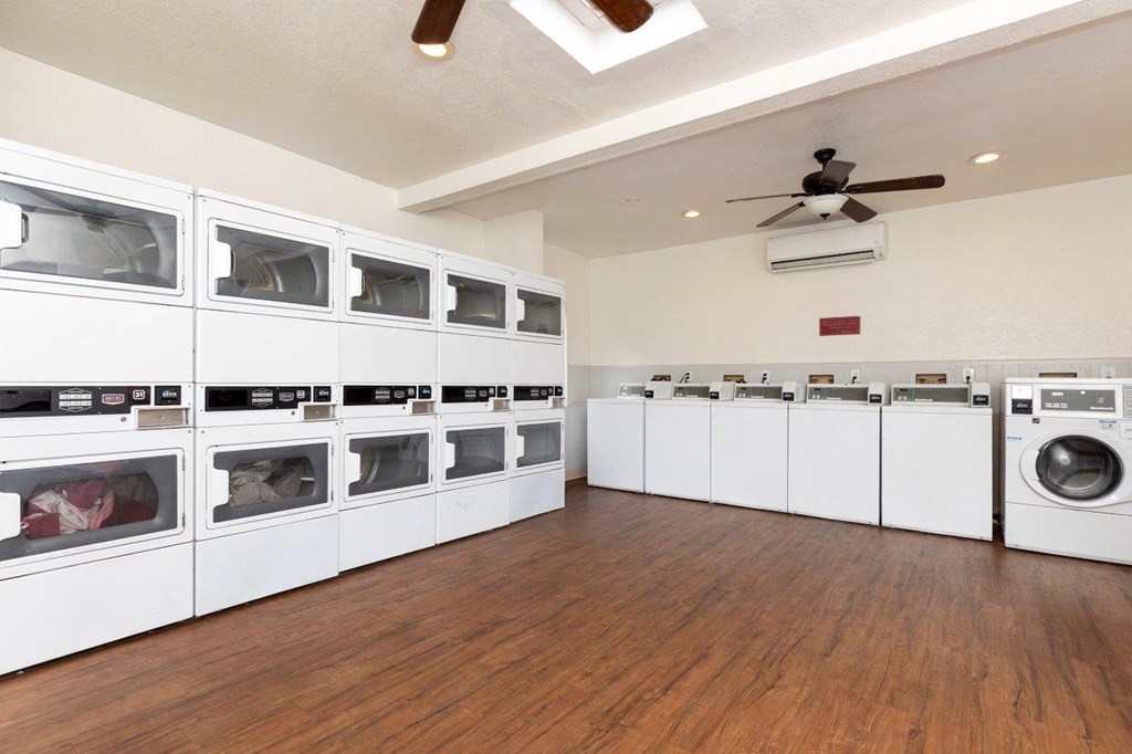 A laundry room with a row of washers and dryers.