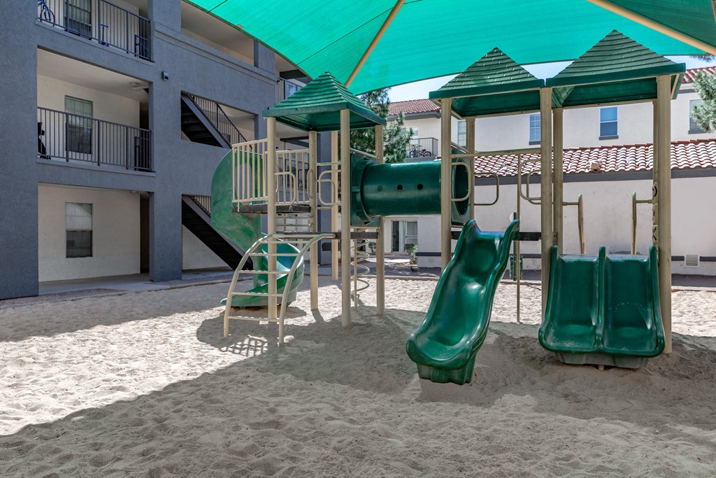 A playground with a green slide and a green canopy.