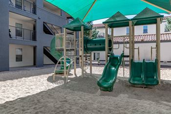 A playground with a green slide and a green canopy.