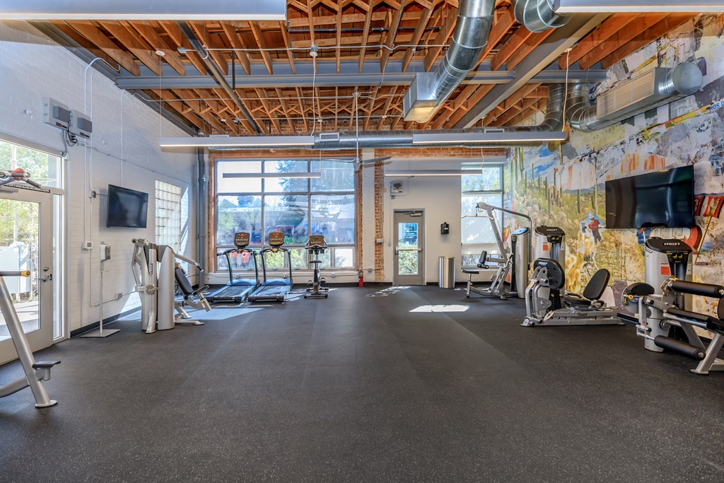 A gym with a variety of equipment including treadmills, weights, and exercise machines.