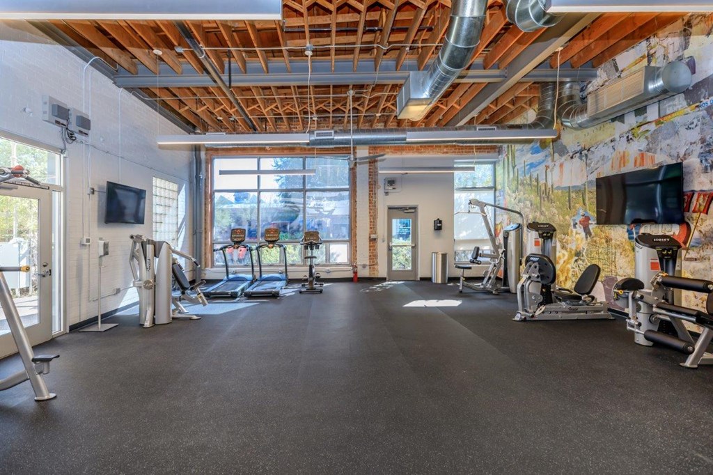 A gym with a variety of equipment including treadmills, weights, and exercise machines.