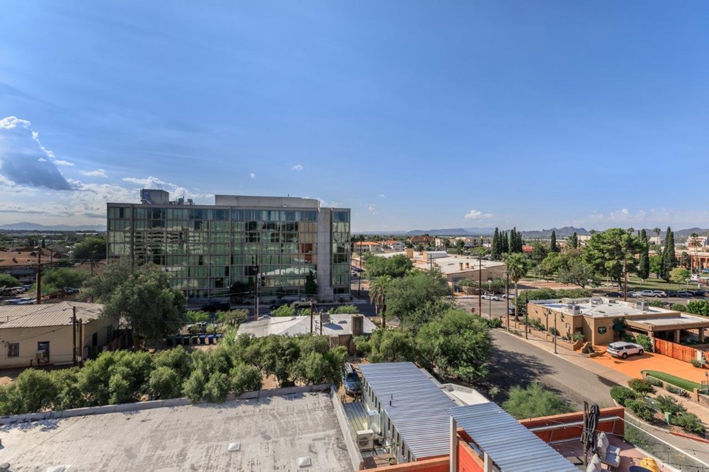 A modern building with a glass facade is the focal point of a sunny, clear day in a suburban area.