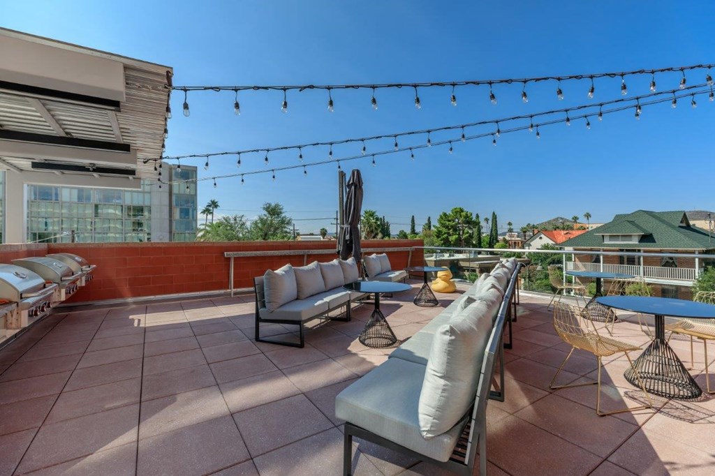 A patio with a string of lights and a few chairs and tables.
