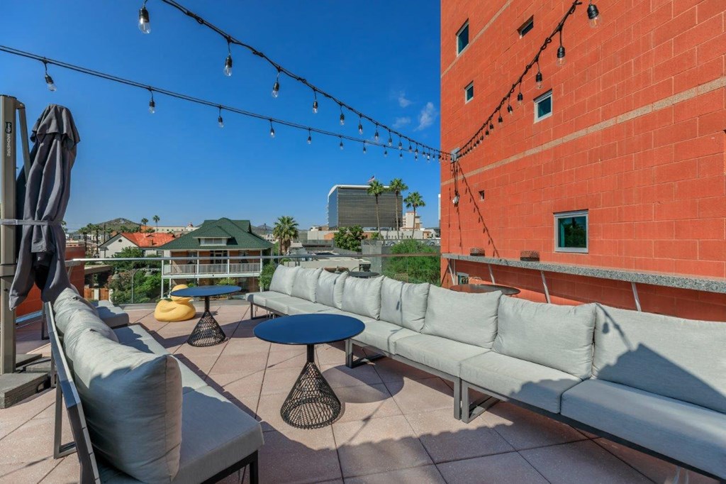 A patio with a table, chairs, and a string of lights.