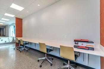 A long white table with chairs and binders on it.