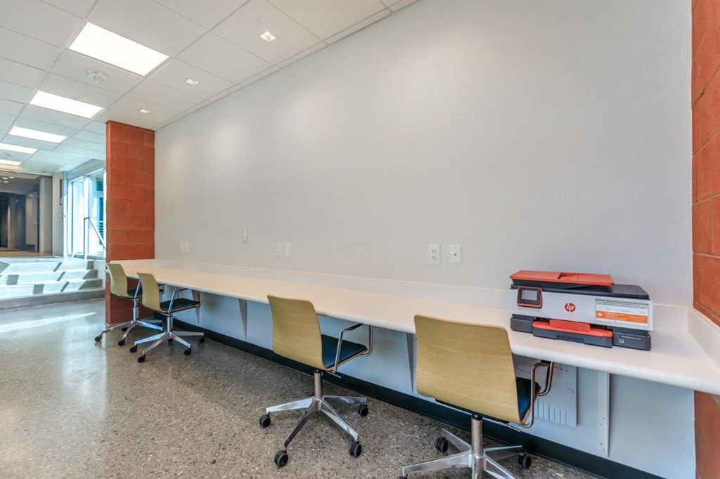 A long white table with chairs and binders on it.