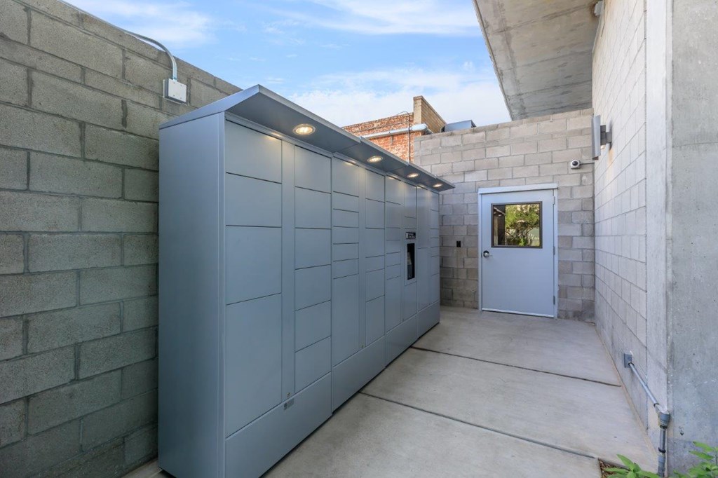 A grey storage unit is in a concrete courtyard.