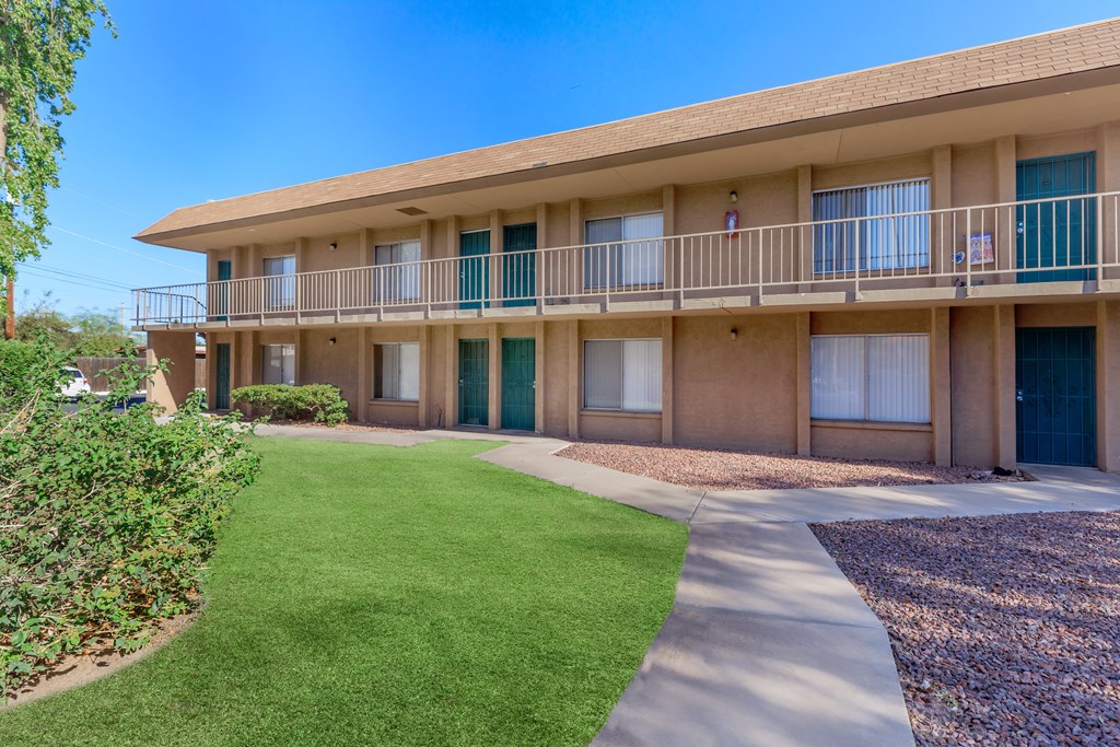 A sunny day at the apartment complex with green grass and bushes.