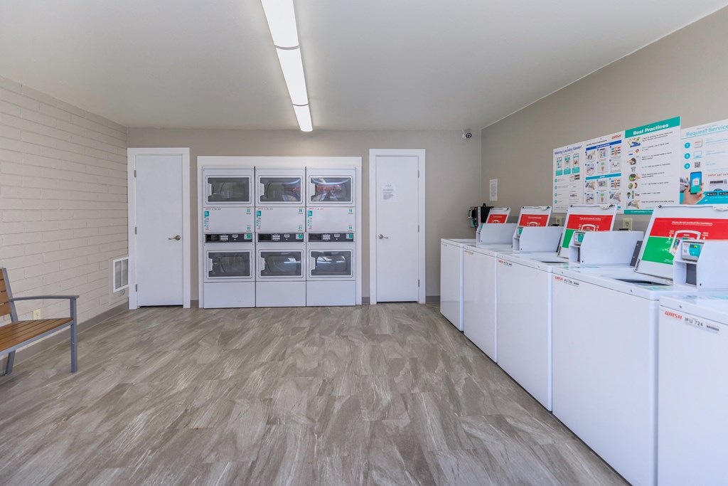 A room with white cabinets and a wall of fridges.