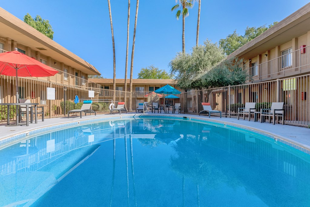 A large swimming pool in a resort with sun loungers and umbrellas.