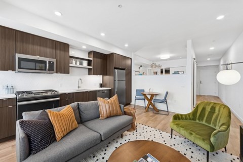 A modern living room with a grey couch and a green armchair.