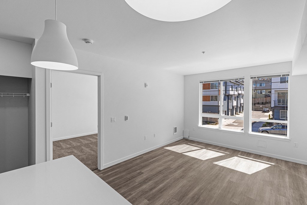 a living room and dining room with white walls and a large window