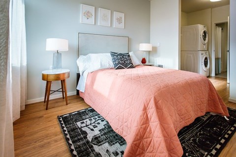 A bedroom with a pink bedspread and a black and white rug.