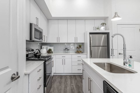 a white kitchen with a sink and a refrigerator