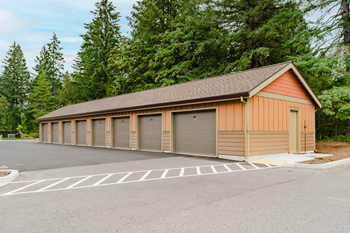 A long building with a brown roof and tan walls with a parking lot in front.