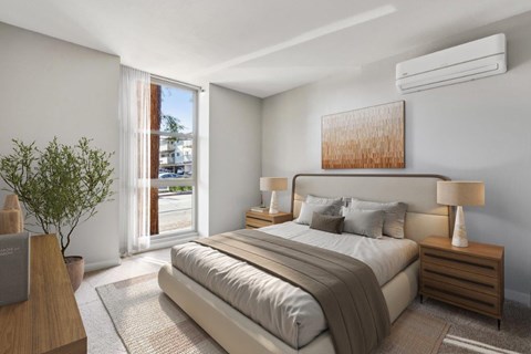 A bedroom with a large bed, a nightstand with a lamp, and a plant.