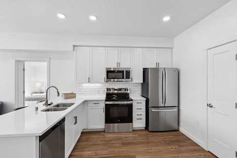 A modern kitchen with white cabinets and stainless steel appliances.