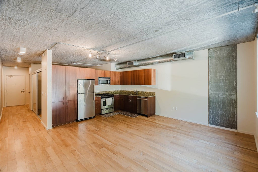 A kitchen area with wooden floors and a refrigerator.