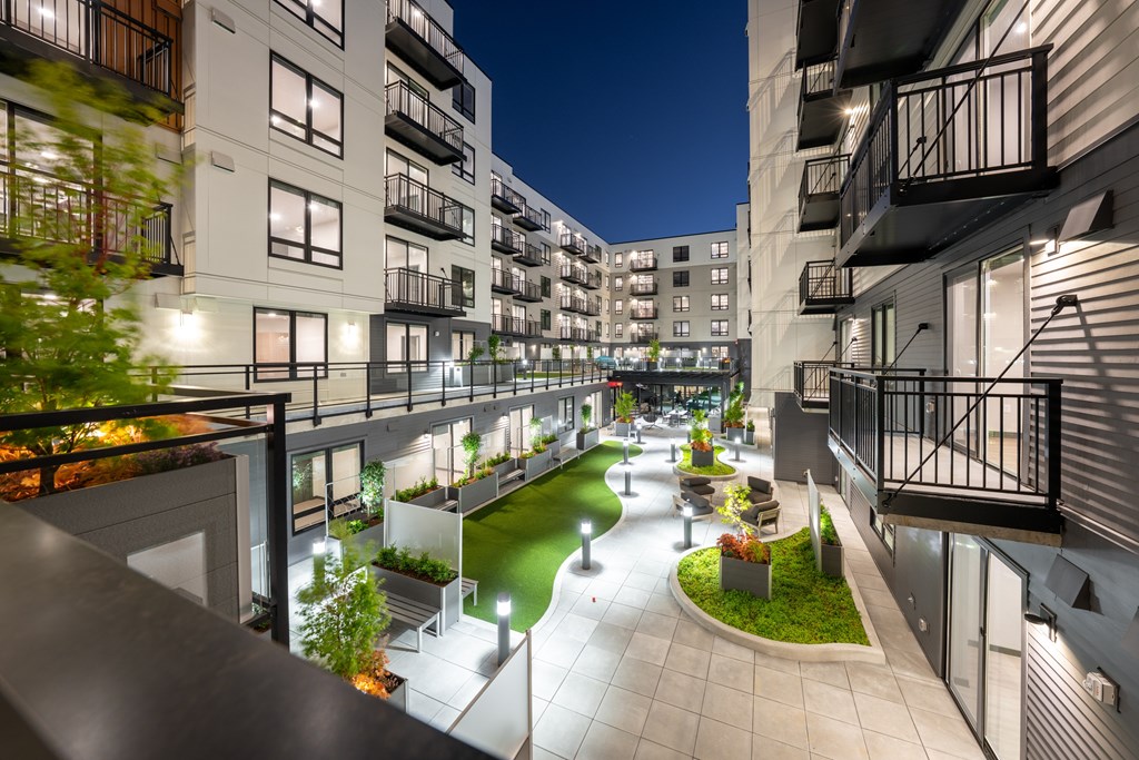A modern apartment complex with a green courtyard and well-lit pathways.