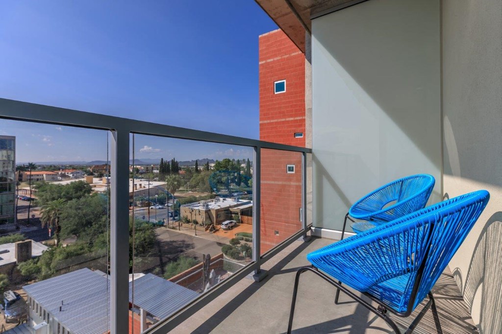 A balcony with a blue chair and a view of the city.