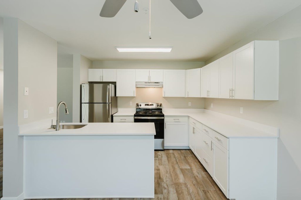 A modern kitchen with white cabinets and a wooden floor.