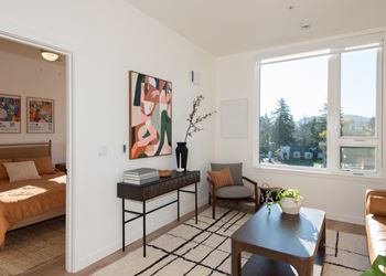 A living room with a sofa, a table, and a painting on the wall.