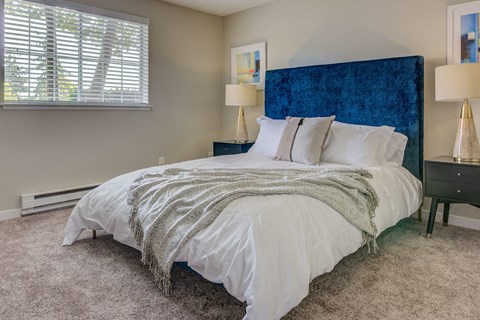 a bedroom with a bed and a blue headboard and a window