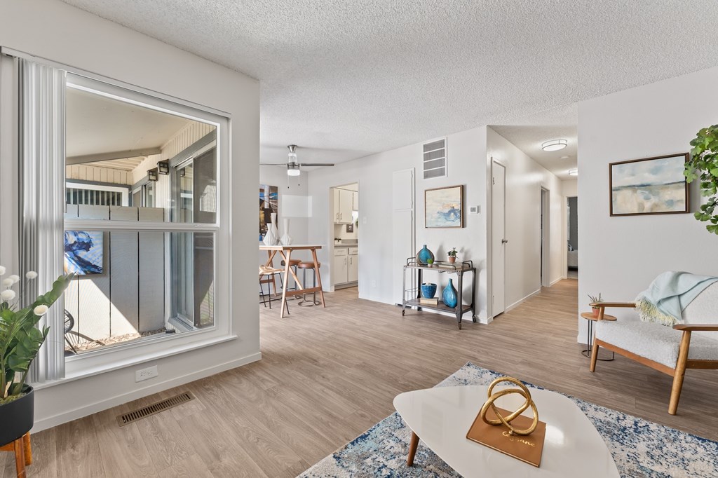 A living room with a white couch and a coffee table with a gold purse on it.
