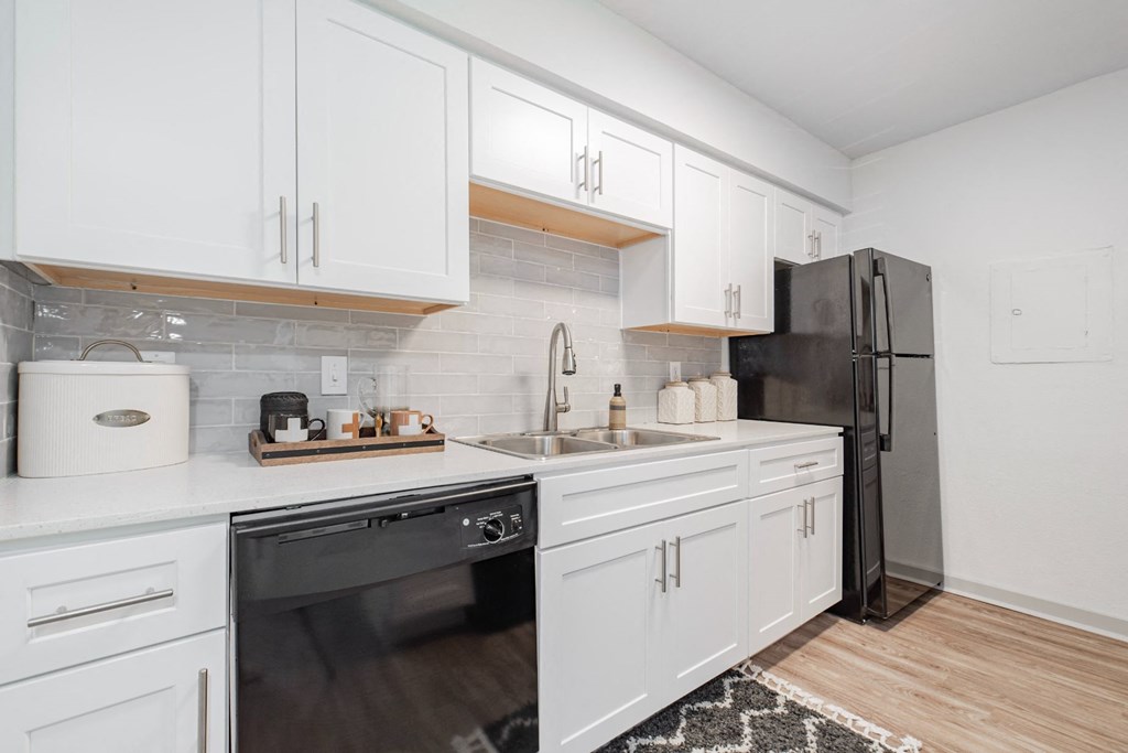 a kitchen with white cabinets and a black refrigerator