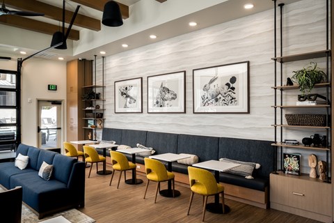 A modern dining area with a blue sofa, yellow chairs, and a white table.