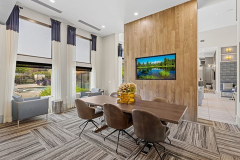 A modern dining room with a wooden panel wall and a television displaying a landscape.