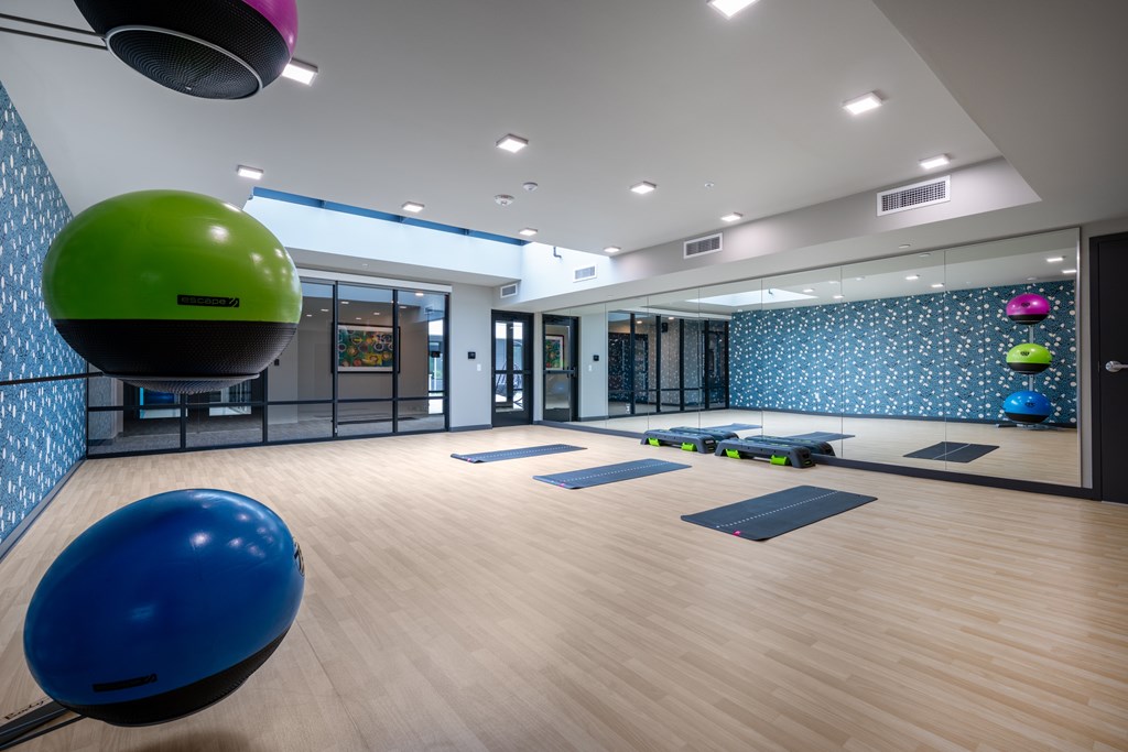 A gym with a blue and green exercise ball on the floor.